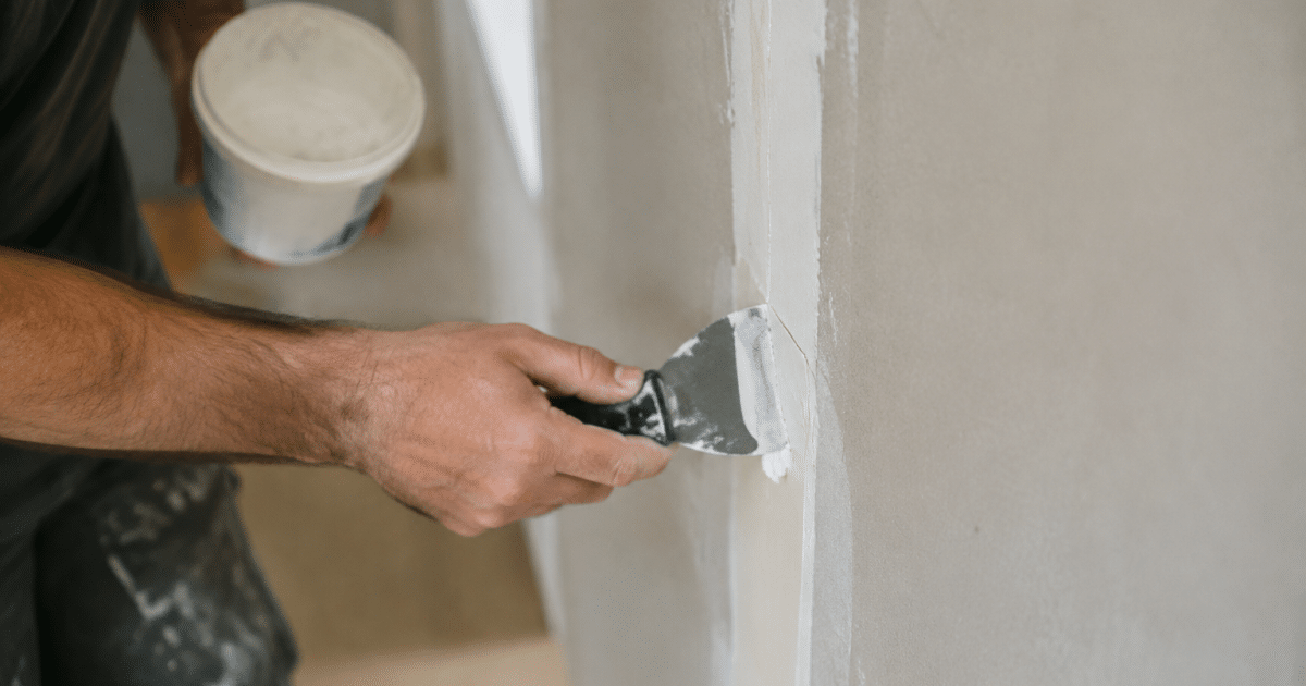 Mains appliquant composé blanc sur joint mur vertical