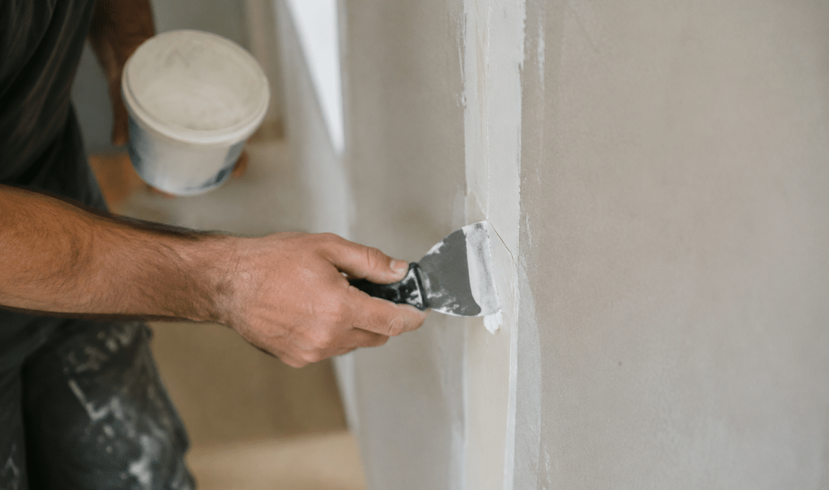 Mains appliquant composé blanc sur joint mur vertical