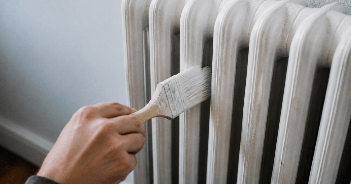 Pinceau appliquant peinture blanche sur radiateur fonte vertical