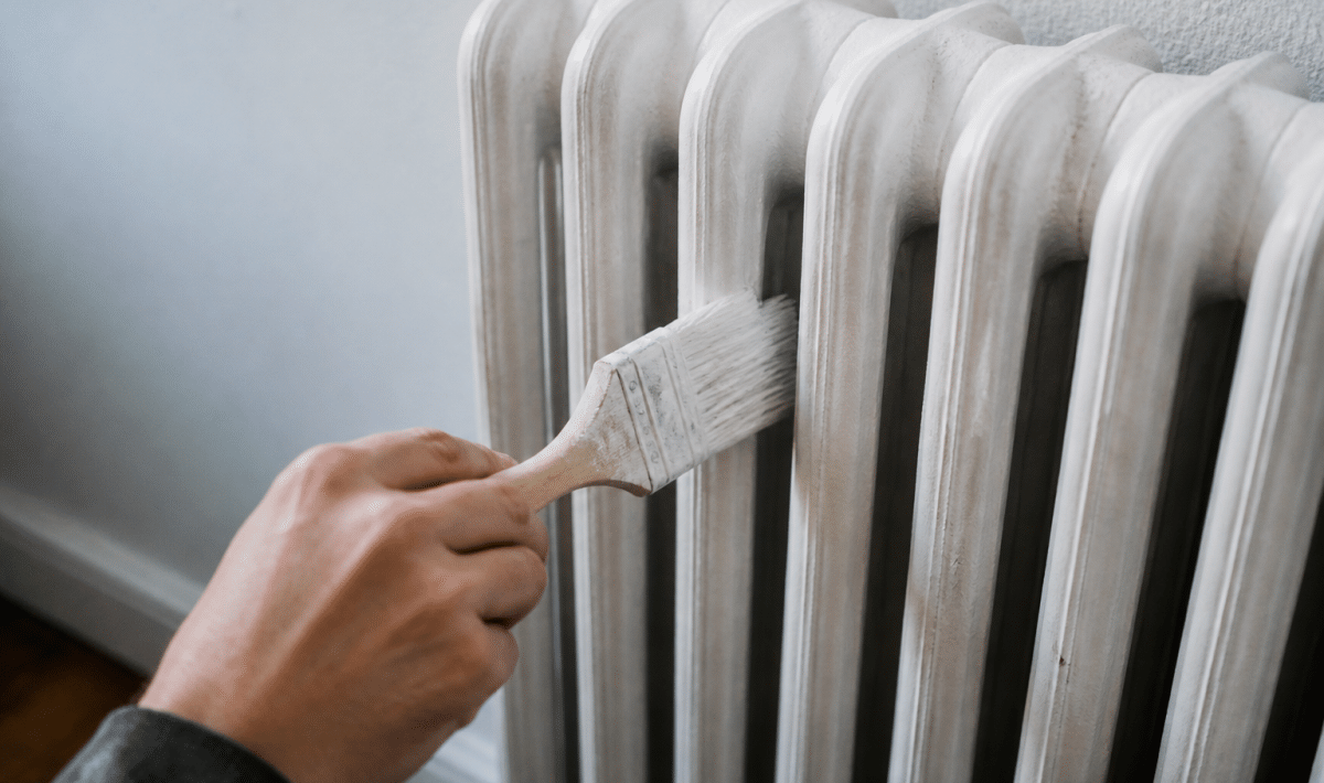 Pinceau appliquant peinture blanche sur radiateur fonte vertical