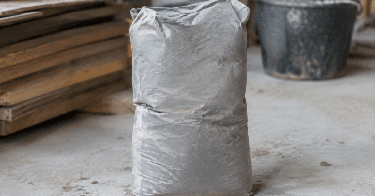 Sac de ciment gris posé verticalement sur sol beton