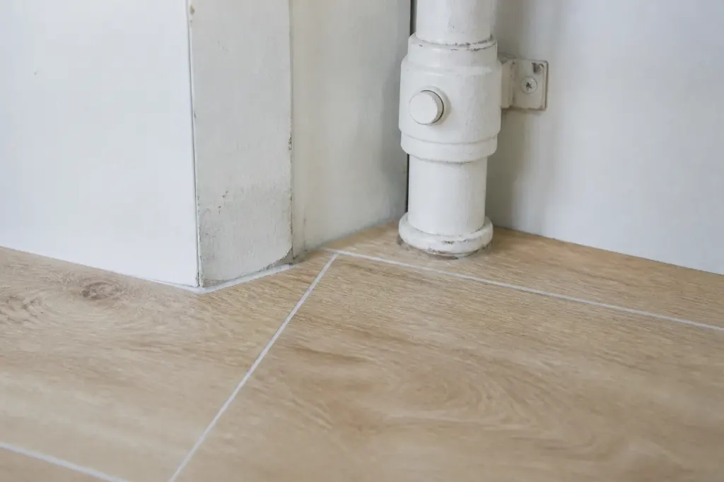 Parquet clair pose avec joint blanc pres du tuyau
