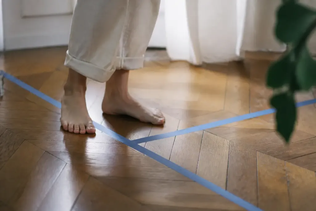 Pieds nus sur parquet avec ruban de masquage bleu