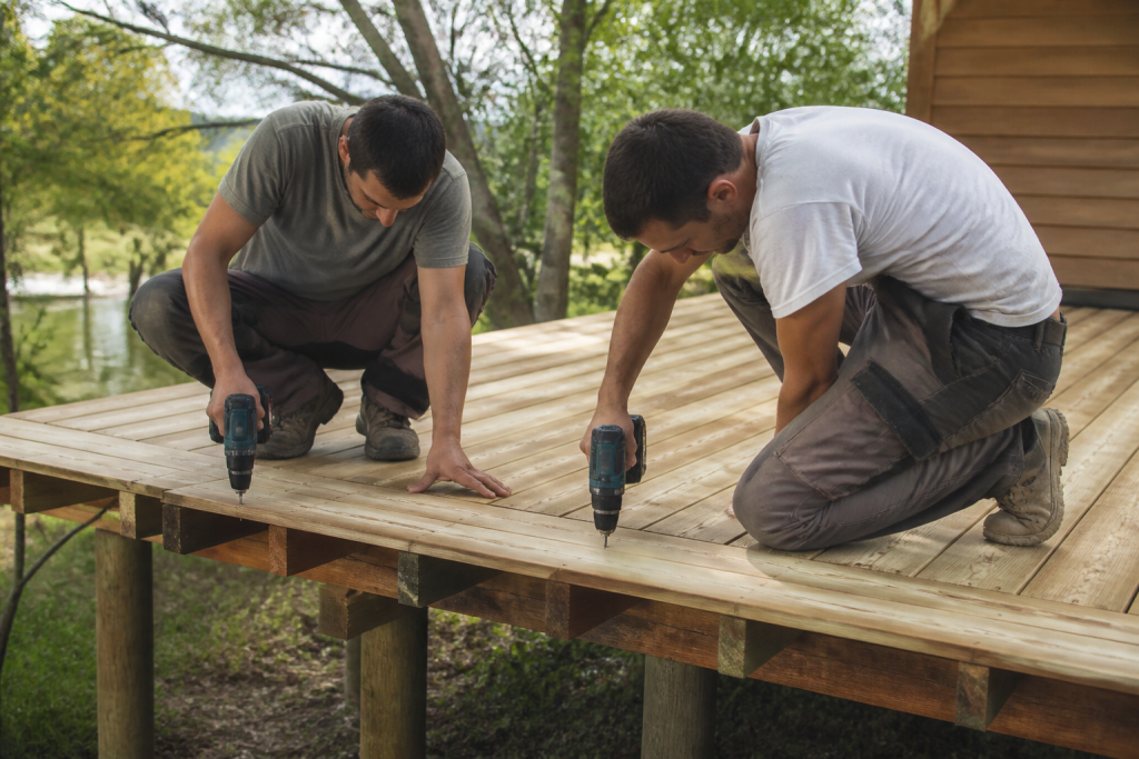Deux ouvriers fixent platelage bois terrasse sur pilotis