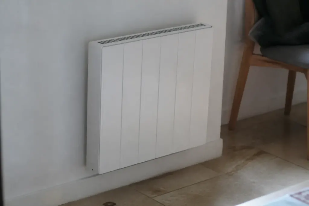 Radiateur électrique blanc fixé sur un mur clair