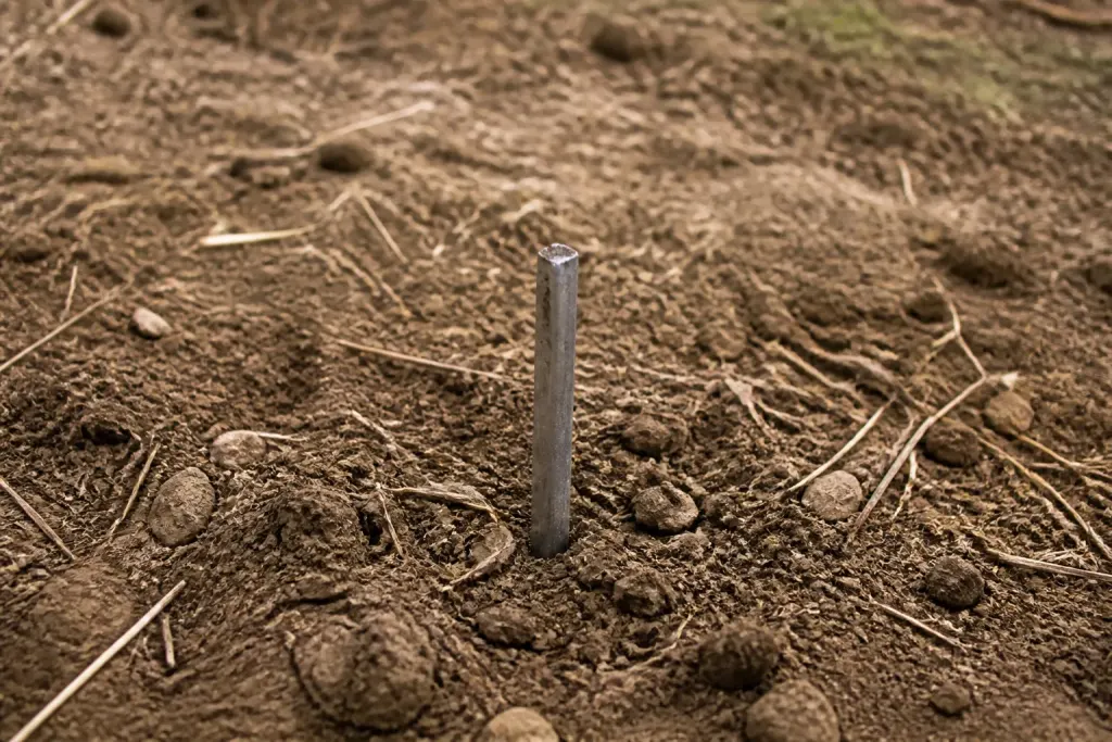 tige metallique enfoncee dans sol brun du terrain